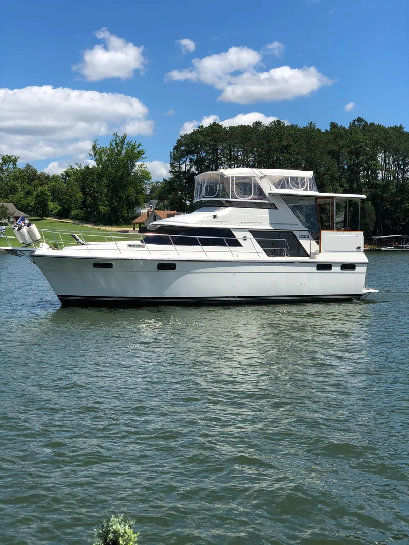Slide: The Image of 1988 Carver 4207MY yacht cruising on a serene lake under a clear blue sky. - 1