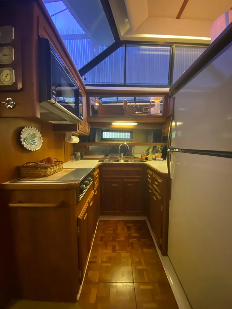 Slide: The Image of 1988 Carver 4207MY yacht kitchen with wood cabinetry, modern appliances, and ample lighting. - 11