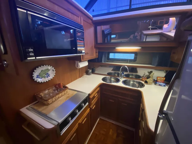Slide: The Image of 1988 Carver 4207MY yacht kitchen with microwave, dual sinks, and wooden cabinetry. - 12