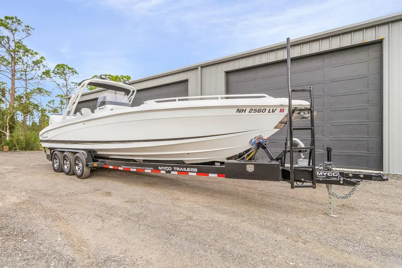 The Image of 2020 Renegade 32' Cuddy boat on trailer, parked outside a large garage. - 1