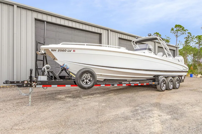 Slide: The Image of 2020 Renegade 32' Cuddy boat on trailer, parked outside a metal building. - 5