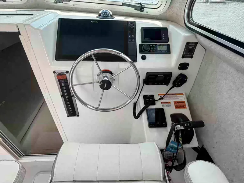 Slide: The Image of 2021 Parker 2520 XLD Sport Cabin helm with steering wheel and navigation controls. - 11