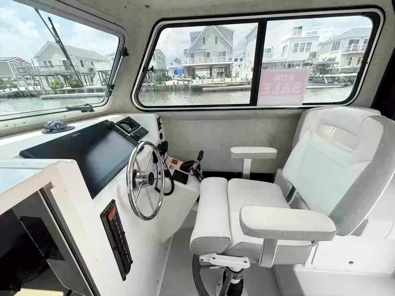 Slide: The Image of Interior of 2021 Parker 2520 XLD Sport Cabin boat, featuring steering wheel and captain's chair. - 12