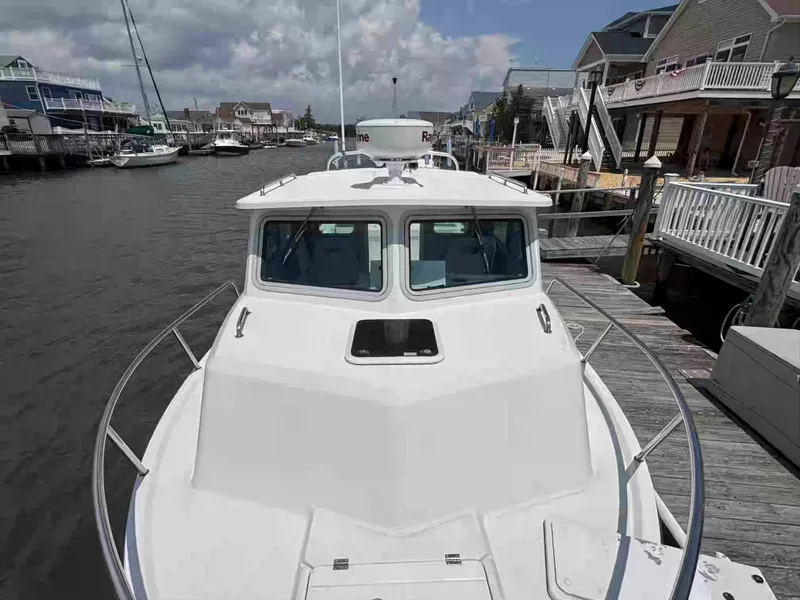 Slide: The Image of 2021 Parker 2520 XLD Sport Cabin boat docked at a marina, surrounded by waterfront homes. - 19