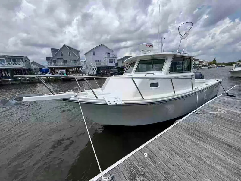 Slide: The Image of 2021 Parker 2520 XLD Sport Cabin boat docked by waterfront homes under cloudy skies. - 4