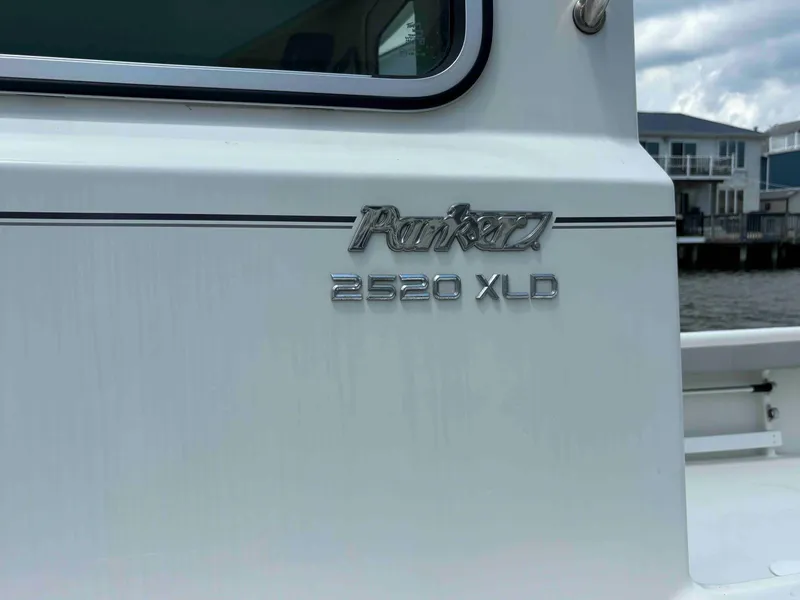Slide: The Image of 2021 Parker 2520 XLD Sport Cabin boat exterior with logo and waterfront view. - 5