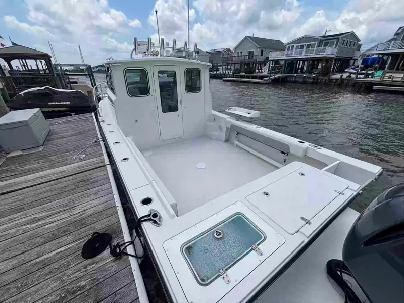 Slide: The Image of 2021 Parker 2520 XLD Sport Cabin boat docked at marina, clear sky, waterfront homes. - 6