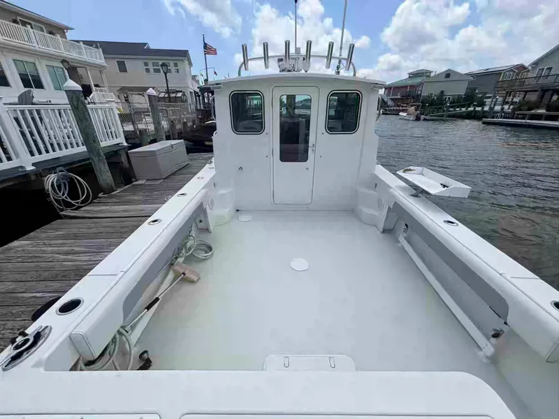 Slide: The Image of 2021 Parker 2520 XLD Sport Cabin boat docked, spacious deck, clear sky, waterfront homes. - 7