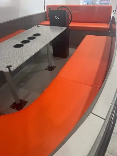 Slide: The Image of 2024 Vision Marine Technologies Volt 180 interior with orange seating and a table with cup holders. - 2
