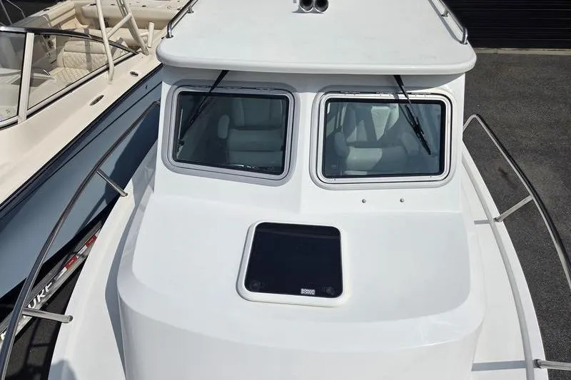 Slide: The Image of 2026 Parker 2421 EXPLORER boat, white exterior, dual windows, docked beside another vessel. - 7