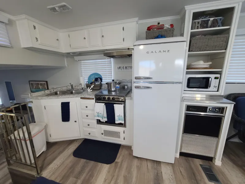 Slide: The Image of Cozy 1977 Stardust Cruisers houseboat interior with wicker chairs and striped cushions. - 7