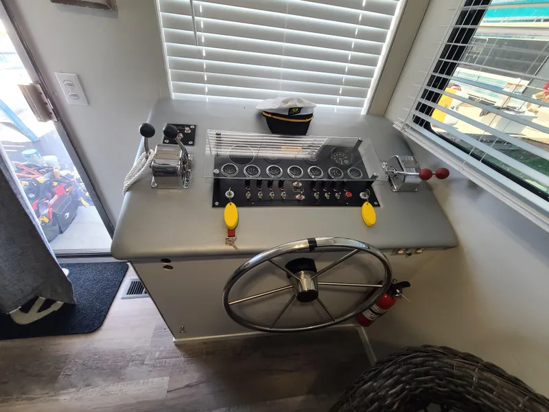 Slide: The Image of Cozy 1977 Stardust Cruisers houseboat interior with wicker chair, striped pillow, and scenic window view. - 8