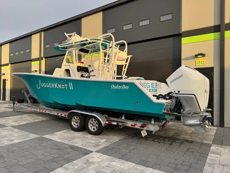 Slide: The Image of 2020 Onslow Bay 33 Tournament boat on trailer, parked outside a garage. - 60