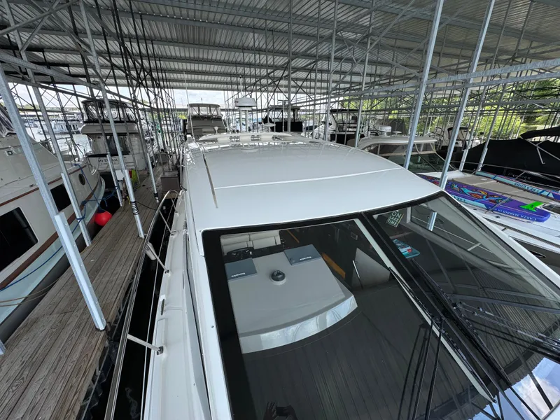 Slide: The Image of 2017 Sea Ray Sundancer 400 docked in a covered marina, surrounded by other boats. - 23