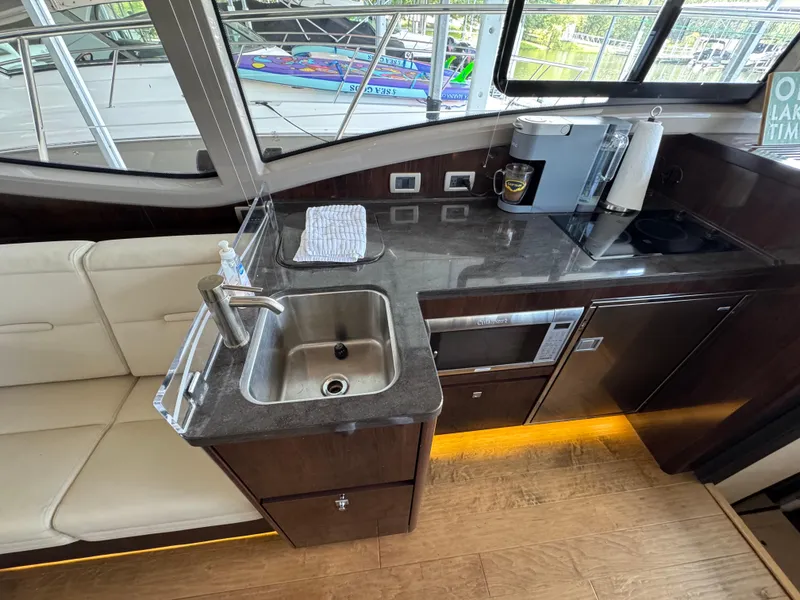 Slide: The Image of 2017 Sea Ray Sundancer 400 yacht interior kitchen with sink, appliances, and seating. - 39