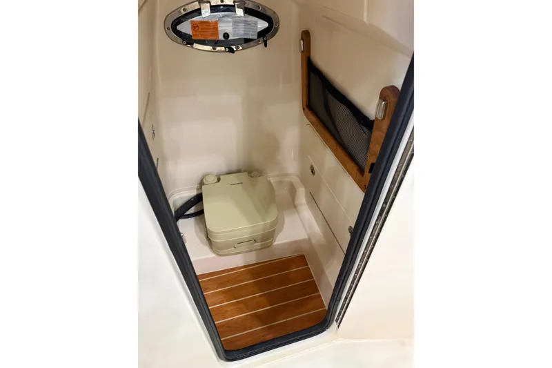 Slide: The Image of 2026 Grady-White Fisherman 236 boat interior with compact toilet and wooden flooring. - 13