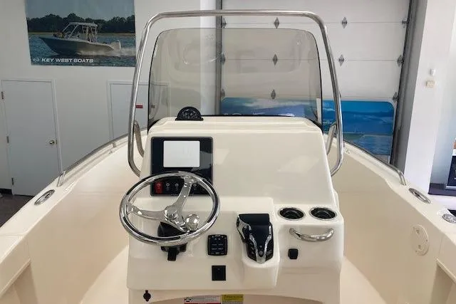 Slide: The Image of 2026 Grady-White Fisherman 180 boat console with steering wheel and controls in showroom. - 3