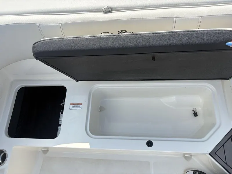 Slide: The Image of 2021 Sea Ray SPX 190 boat storage compartments with open lid, showcasing interior space. - 12