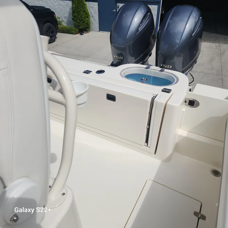 Slide: The Image of 2018 Cobia 261 Center Console boat with twin engines and storage compartment. - 10