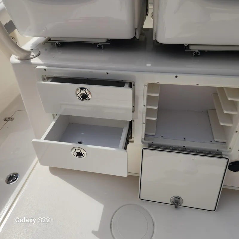 Slide: The Image of 2018 Cobia 261 Center Console storage compartments with open drawers and shelves. - 14