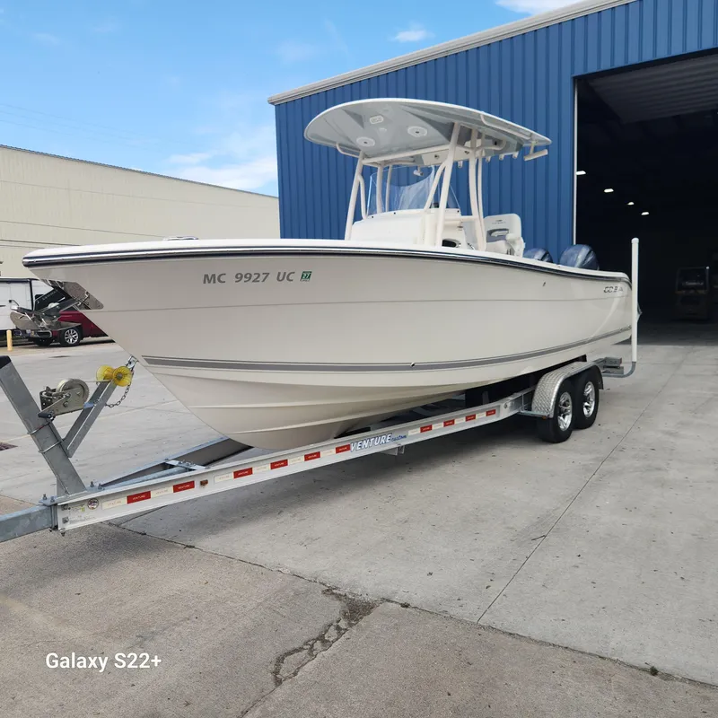 Slide: The Image of 2018 Cobia 261 Center Console boat on trailer outside blue warehouse. - 3