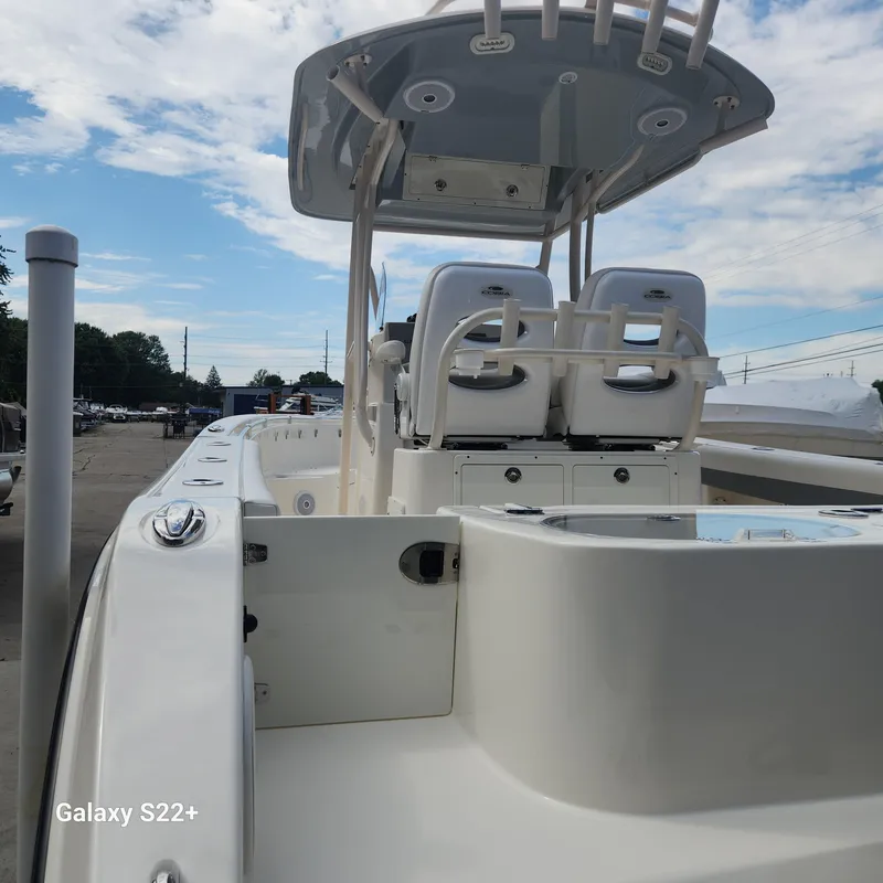 Slide: The Image of 2018 Cobia 261 Center Console boat with dual seats and T-top under a blue sky. - 32
