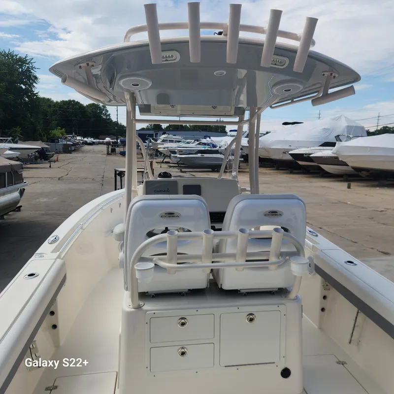 Slide: The Image of 2018 Cobia 261 Center Console boat with dual seats and rod holders, docked outdoors. - 7
