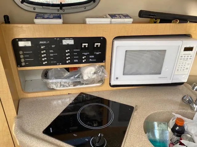 Slide: The Image of 2005 Boston Whaler 275 Conquest kitchen with microwave, stove, and control panel. - 13