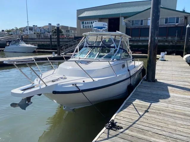 Slide: The Image of 2005 Boston Whaler 275 Conquest docked at marina under clear sky. - 2