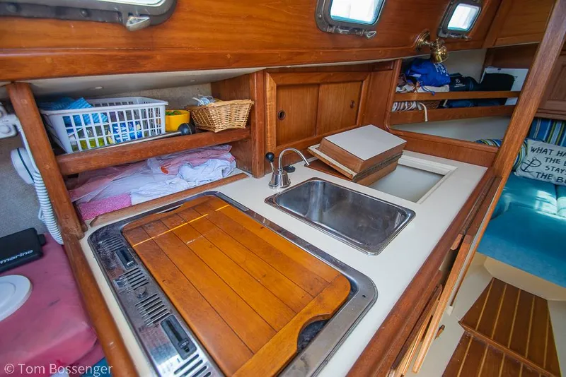 Slide: The Image of Cozy 1993 Pacific Seacraft Flicka 20 yacht interior with wooden cabinetry and compact kitchen area. - 10