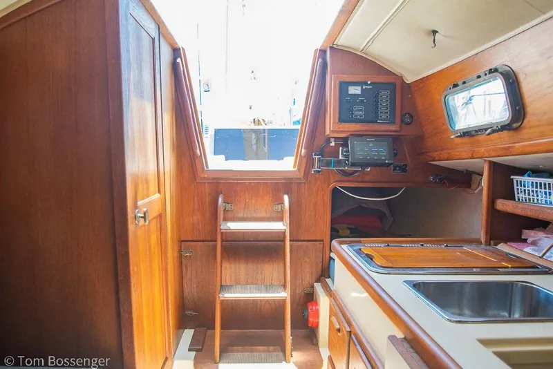 Slide: The Image of Interior of 1993 Pacific Seacraft Flicka 20 sailboat, featuring wooden cabinetry and compact kitchen area. - 17