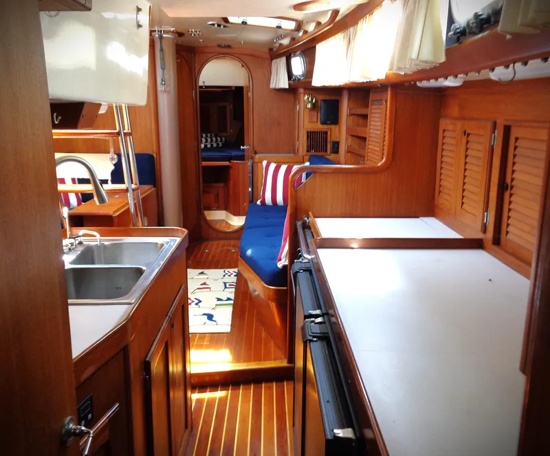 Slide: The Image of 1983 Bristol 41.1 yacht interior with wooden finish, kitchenette, and seating area. - 2