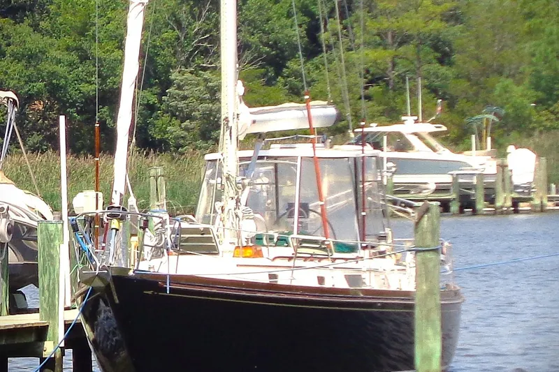 Slide: The Image of Sailboat docked at marina, Bristol 41.1 model, 1983, surrounded by lush greenery. - 16
