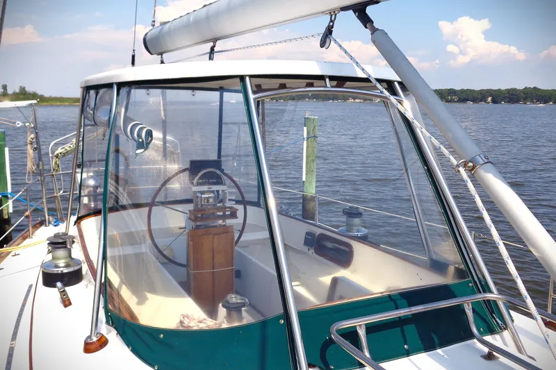 Slide: The Image of 1983 Bristol 41.1 sailboat cockpit with steering wheel, docked on a calm lake. - 11