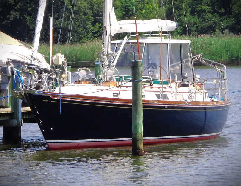The Image of 1983 Bristol 41.1 sailboat docked on a calm river with lush greenery. - 10
