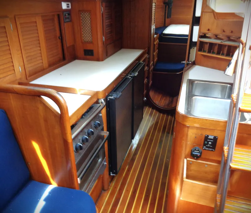 Slide: The Image of 1983 Bristol 41.1 yacht interior with wooden cabinetry, compact kitchen, and cozy seating area. - 5
