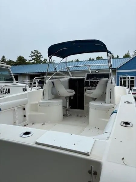 Slide: The Image of 1995 Wellcraft 238 Coastal boat interior with seating and canopy, docked near blue building. - 6