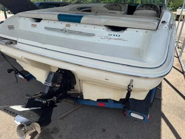 Slide: The Image of 1998 Sea Ray 210 Signature boat, rear view, on trailer, showcasing outboard motor and sleek design. - 3