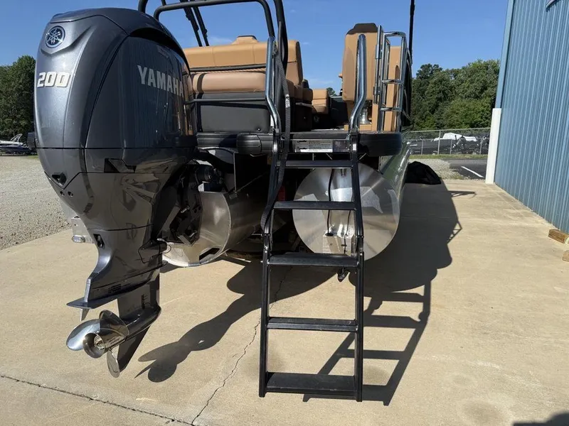 Slide: The Image of 2025 Godfrey Monaco 235 SFL boat with Yamaha 200 engine and ladder, parked outdoors. - 24