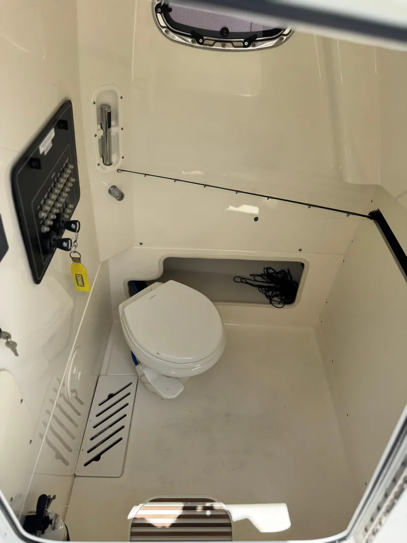 Slide: The Image of 2020 Boston Whaler 280 Outrage interior cabin with toilet and control panel. - 34