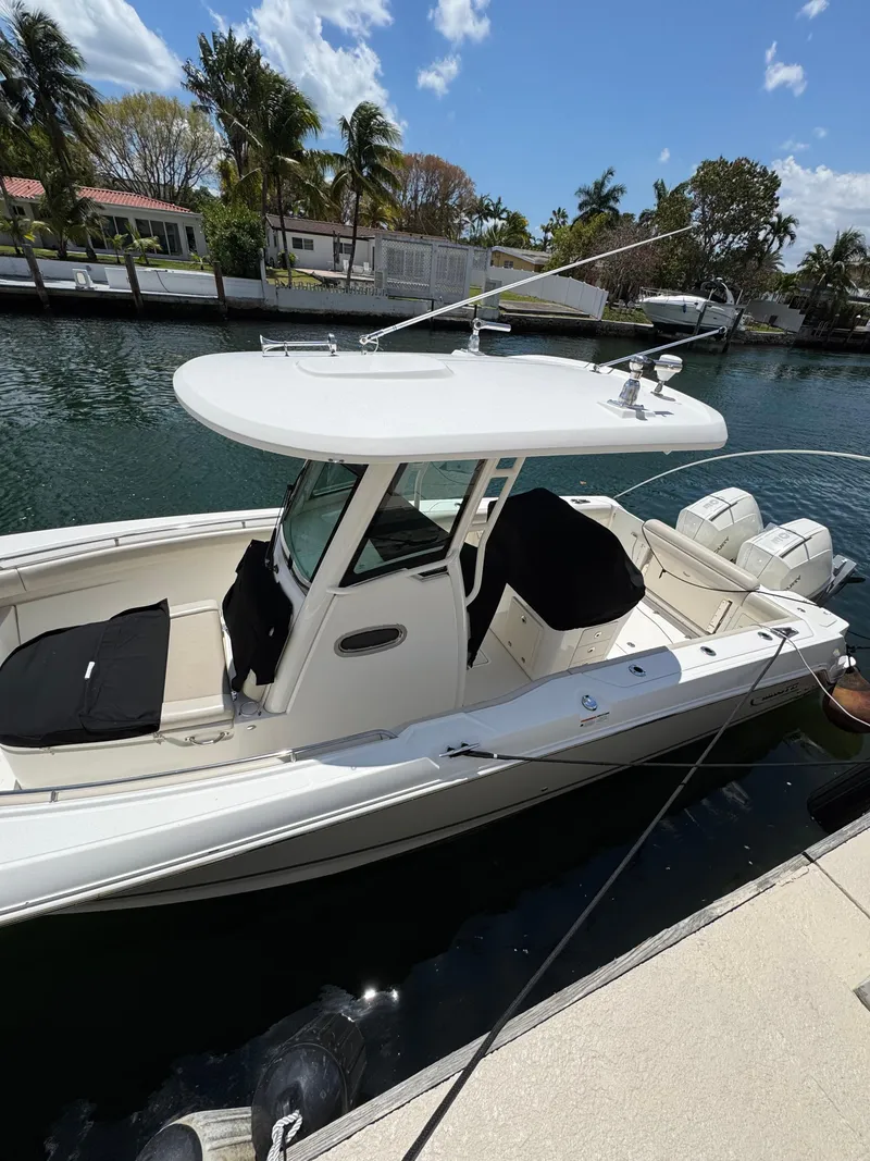 Slide: The Image of 2020 Boston Whaler 280 Outrage docked by a canal with palm trees. - 6