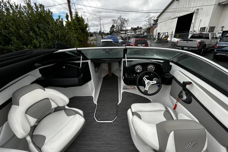 Slide: The Image of 2021 Four Winns HD2 OB boat interior with steering wheel and seating, parked outdoors. - 16