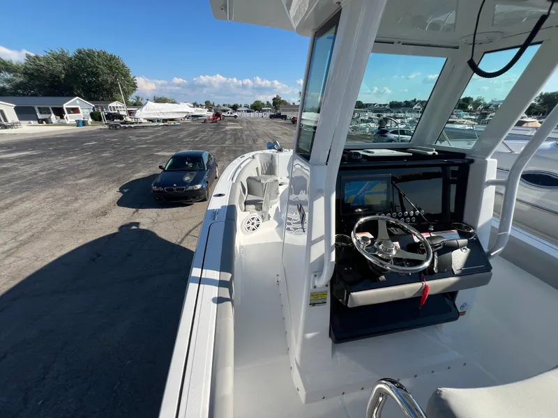 Slide: The Image of 2026 Wellcraft 243 Fisherman boat with steering console, parked near a marina. - 15