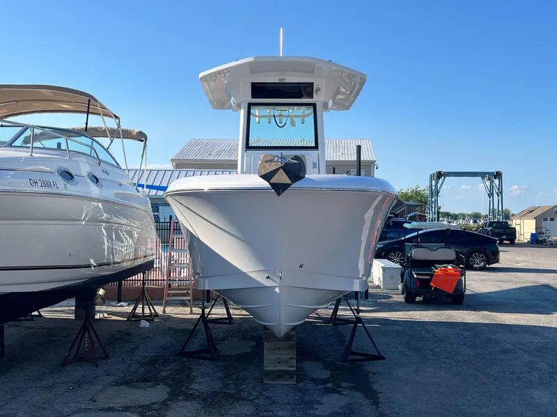 Slide: The Image of 2026 Wellcraft 243 Fisherman boat on display at a marina, clear blue sky. - 2