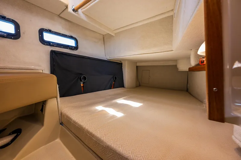 Slide: The Image of 2021 Ranger Tugs R-31 CB cabin interior with beige upholstery and small windows. - 11