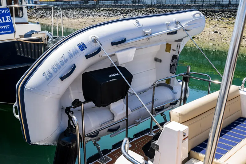 Slide: The Image of 2021 Ranger Tugs R-31 CB with inflatable dinghy on deck, docked by the water. - 14