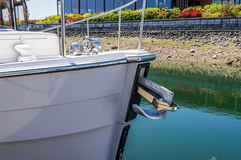 Slide: The Image of 2021 Ranger Tugs R-31 CB boat bow with anchor, docked near a rocky shoreline. - 17