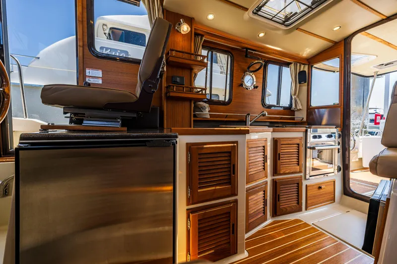 Slide: The Image of Interior of 2021 Ranger Tugs R-31 CB, featuring wood cabinetry and modern appliances. - 27