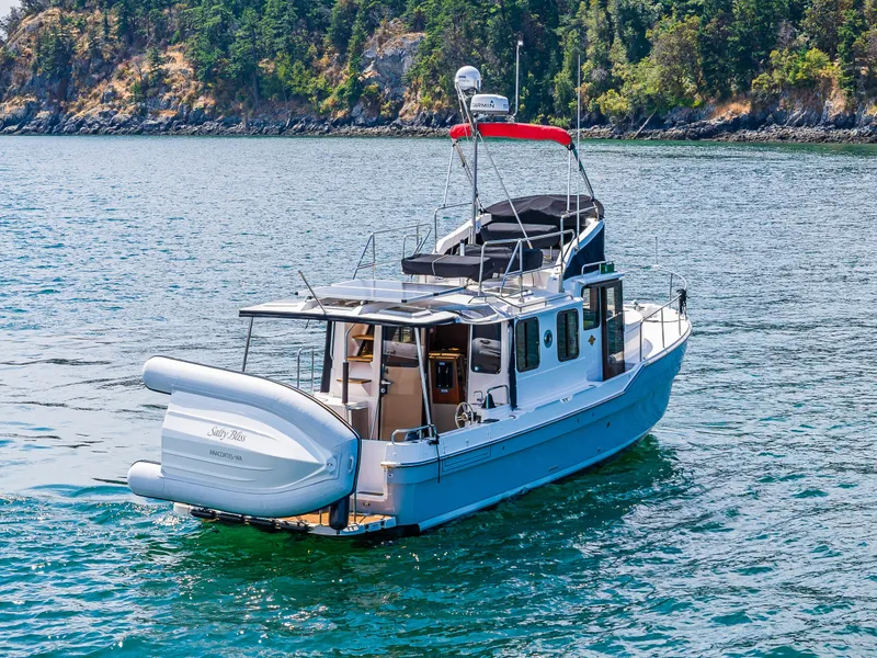 Slide: The Image of 2021 Ranger Tugs R-31 CB boat on scenic water with lush green shoreline. - 7
