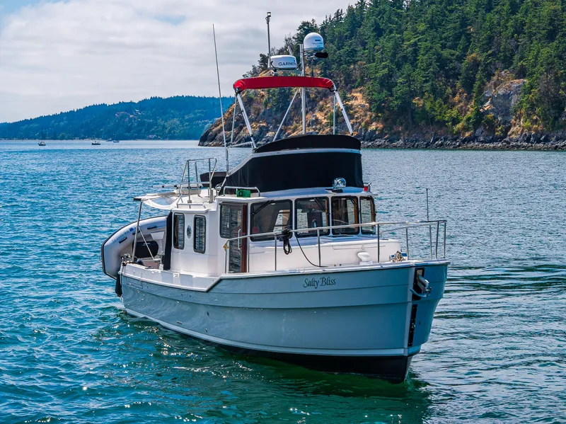 Slide: The Image of 2021 Ranger Tugs R-31 CB boat cruising near a forested coastline. - 8